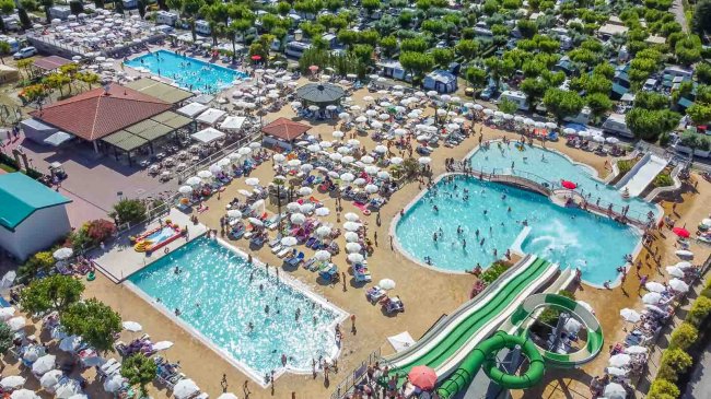 Piscine affollate con scivoli e ombrelloni.