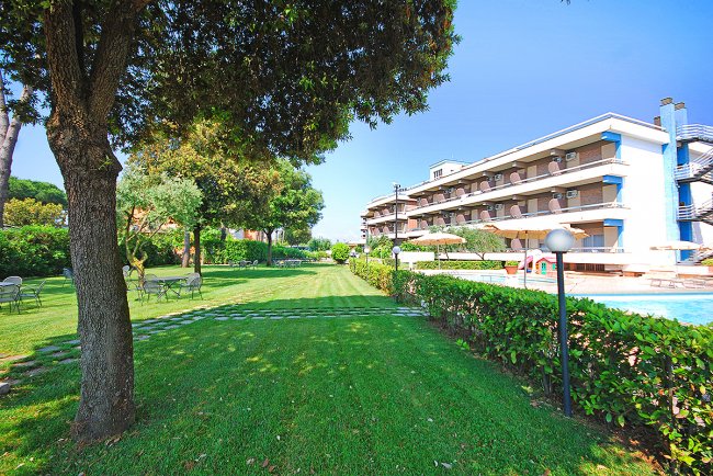 Giardino verde con prato e alberi vicino a un edificio.