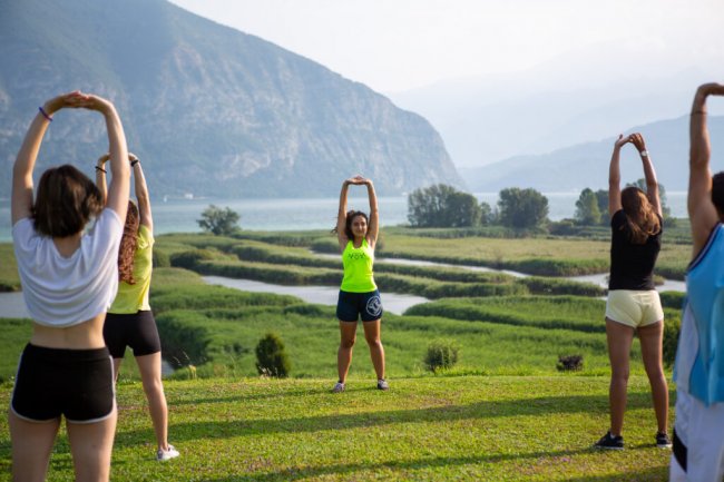 Gruppo di persone che fa stretching con vista lago.