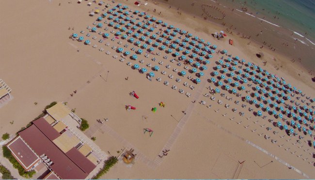 Spiaggia con ombrelloni blu disposti in fila.