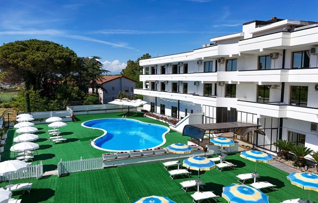 Hotel con piscina e numerosi lettini e ombrelloni.