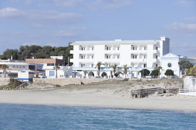Hotel bianco fronte mare con palme.