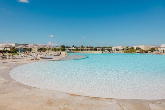 Piscina all’aperto con lettini sotto un cielo limpido.