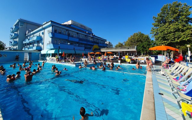 Piscina affollata con ombrelloni arancioni.