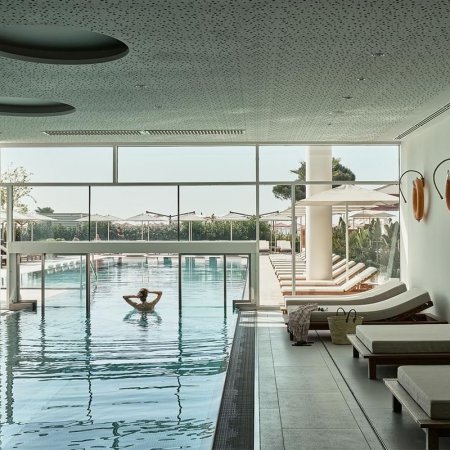 Piscina coperta con lettini e ampie finestre.