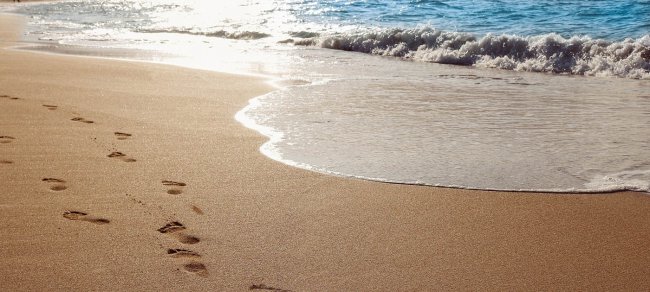 Impronte su una spiaggia al tramonto.