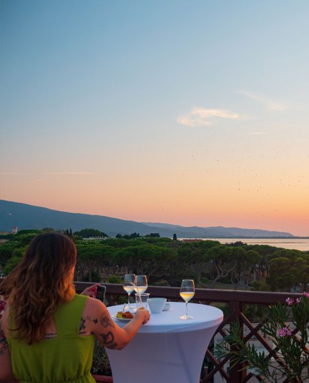 Persona a un tavolo all'aperto con vista sul tramonto.