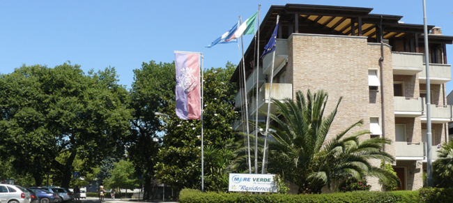 Edificio in mattoni con bandiere e palme.