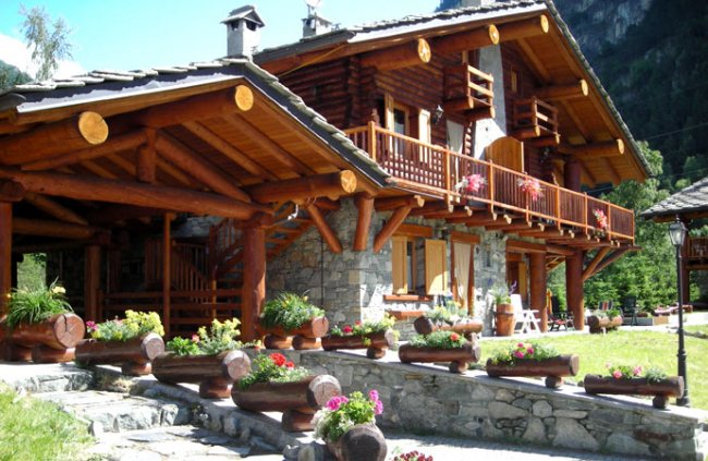 Chalet rustico con balcone fiorito e tetto in legno, immerso nella natura.