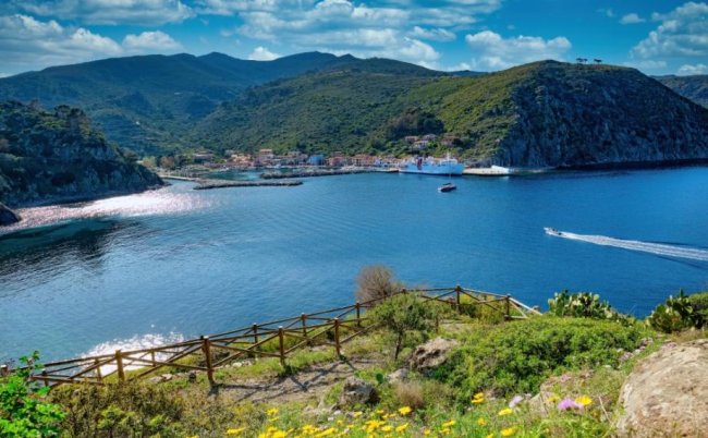 Baia con acqua blu e colline verdi sullo sfondo.
