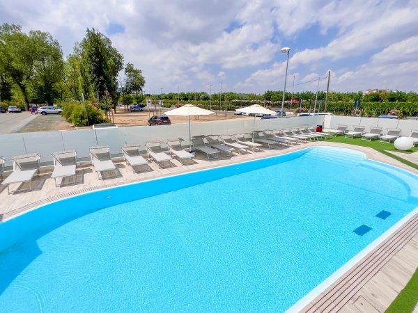 Piscina azzurra con lettini e ombrelloni.