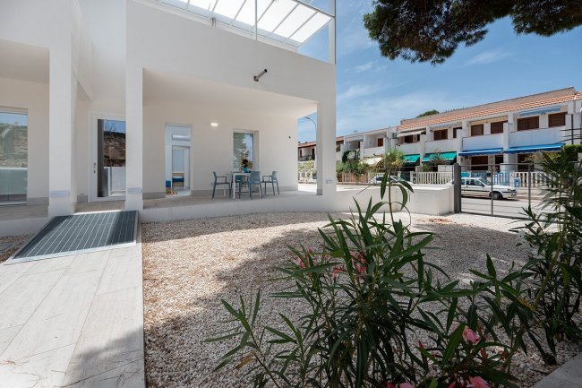 Terrazza esterna con tavolo e sedie, giardino con ghiaia.