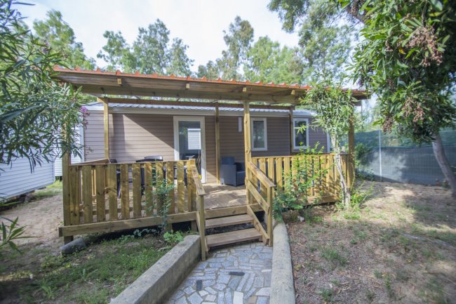 Bungalow con veranda e giardino alberato.