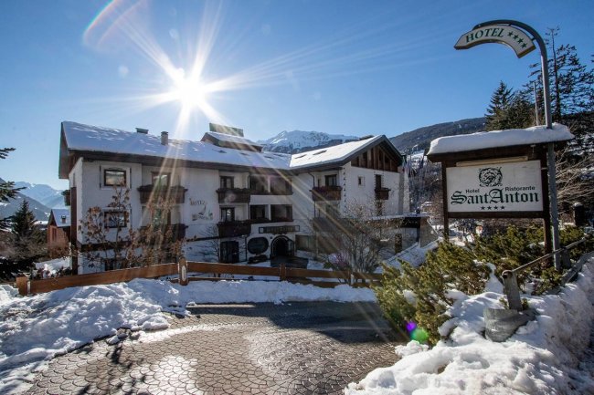 Hotel innevato sotto un cielo soleggiato.