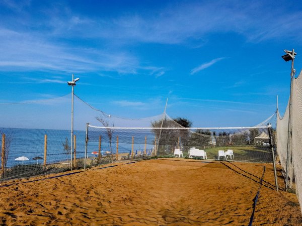 Campo da beach volley con rete e sedie bianche.