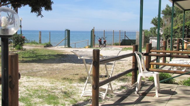 Vista sul mare con sedie bianche e tavolo.