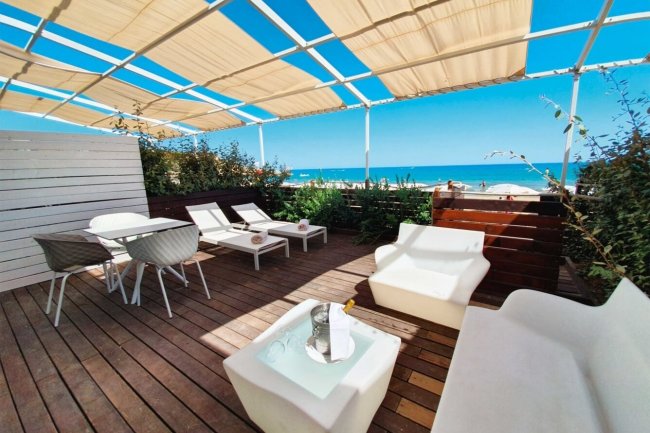 Terrazza sul mare con lettini e sedie.