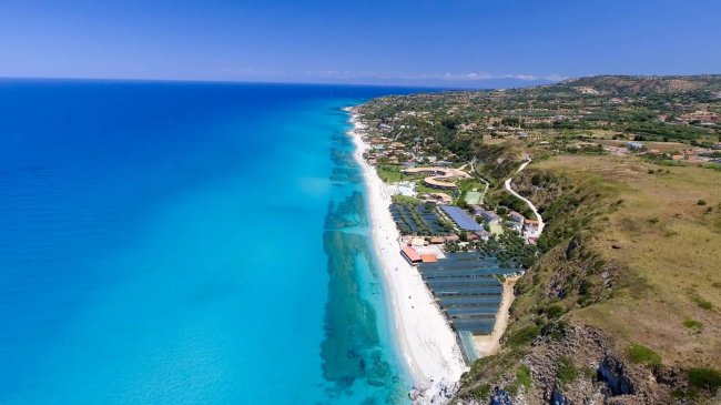 Spiaggia con mare turchese e costa verde.
