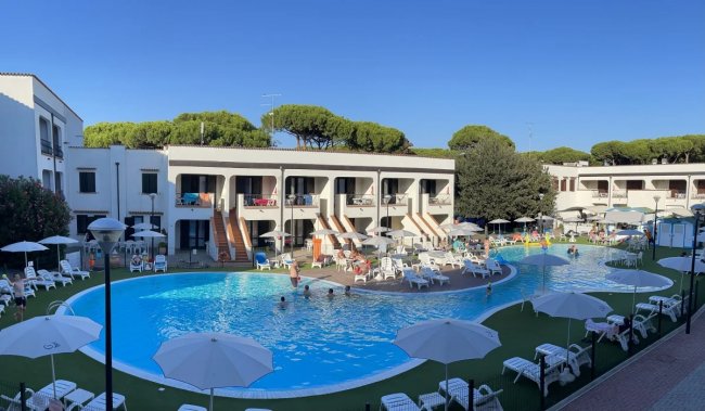 Piscina circondata da lettini e ombrelloni bianchi.