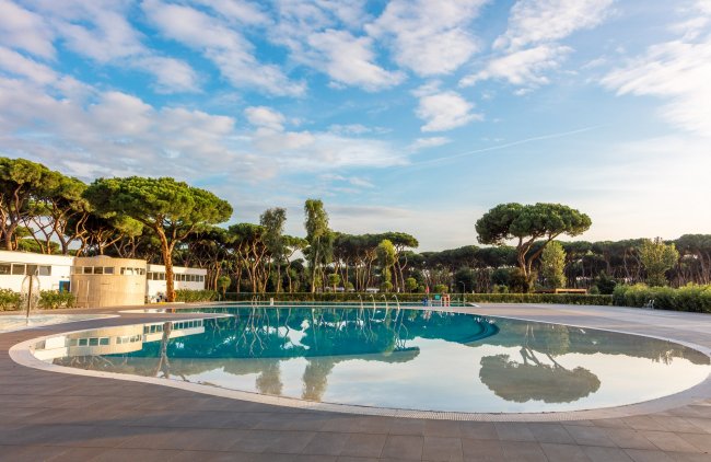 Piscina circondata da alberi al tramonto.