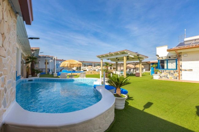 Piscina all'aperto con giardino e pergola.