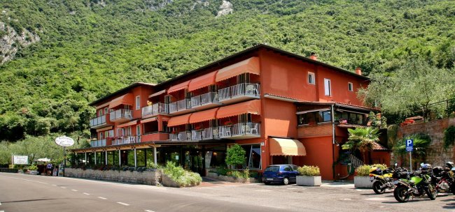 Hotel arancione con balconi su strada e montagne.