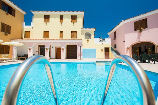 Piscina davanti a un edificio colorato con finestre in legno.