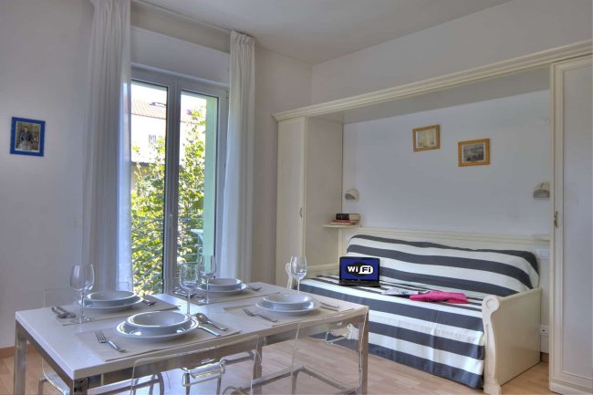 Soggiorno con tavolo apparecchiato e divano a righe.