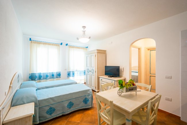 Soggiorno luminoso con due letti e tavolo.