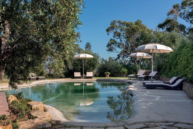 Piscina all'aperto circondata da lettini e ombrelloni.