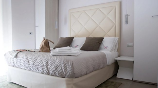 Letto con testiera trapuntata e cuscini marroni.