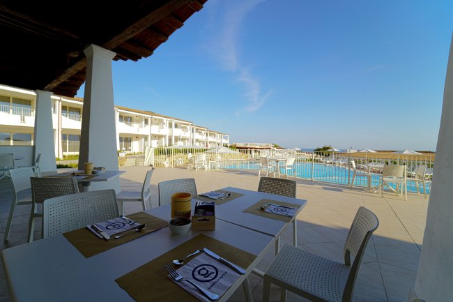 Terrazza con tavoli apparecchiati e vista piscina.