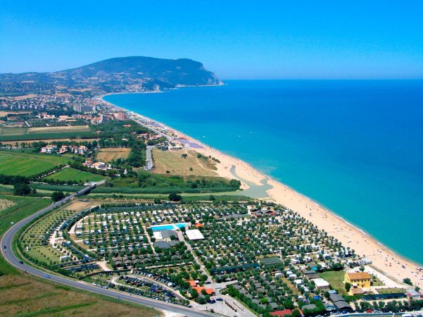 Vista aerea di una spiaggia e un villaggio turistico vicino al mare.
