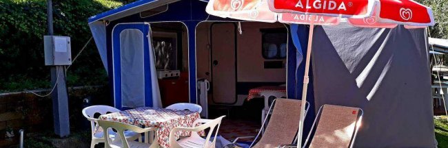 Una tenda da campeggio con sedie e ombrello rosso.