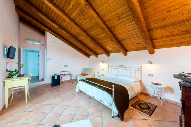 Camera con letto matrimoniale sotto un soffitto di legno.