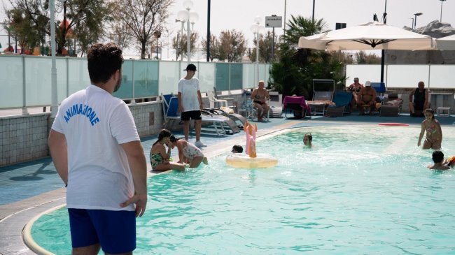 Piscina all'aperto con persone e animatore.