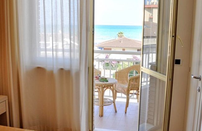 Balcone con vista mare, tavolino e sedie di vimini.