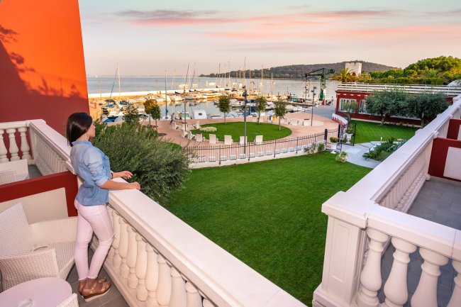 Donna su balcone con vista su giardino e porto.