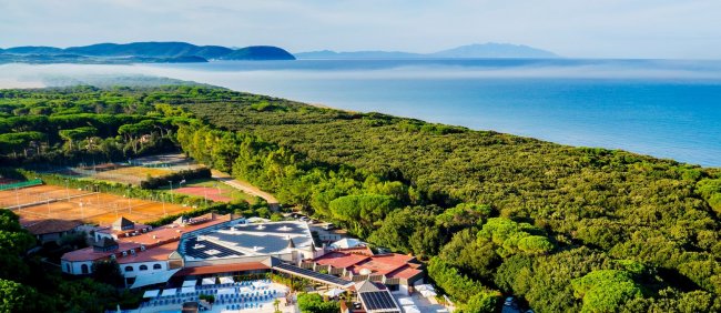 Vista aerea di un resort vicino a una lunga spiaggia e foresta.