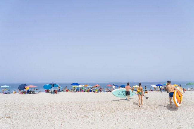 Spiaggia affollata con ombrelloni colorati.