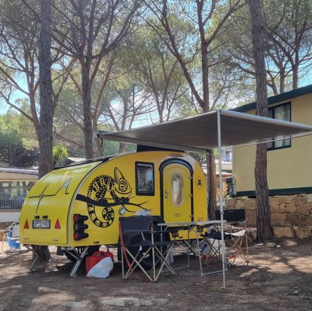 Roulotte gialla con tavolo sotto tendalino.