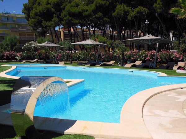 Piscina all'aperto con lettini e ombrelloni.