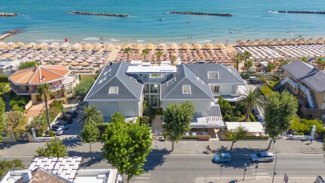 Complesso residenziale fronte spiaggia con ombrelloni.