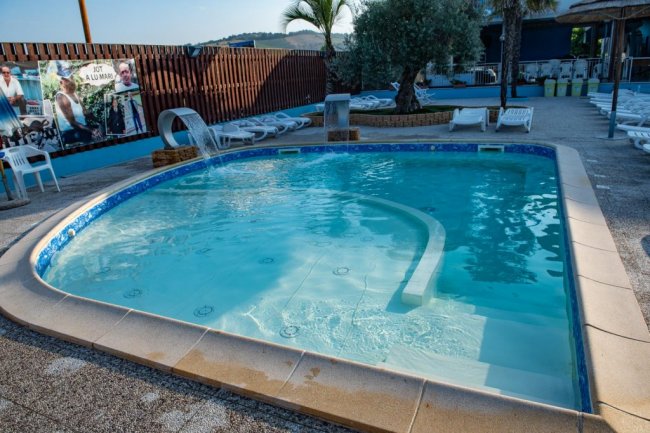 Piscina piccola con lettini intorno.