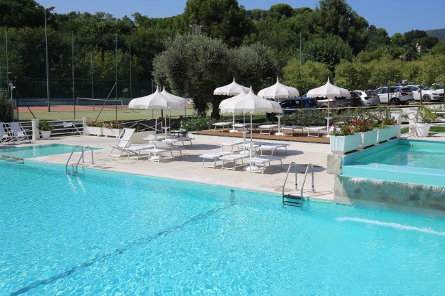 Piscina con lettini e ombrelloni bianchi.