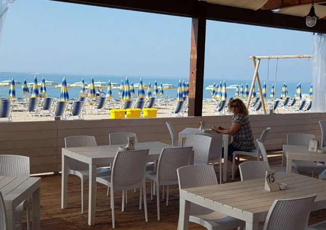 Ristorante sulla spiaggia con vista mare e ombrelloni.