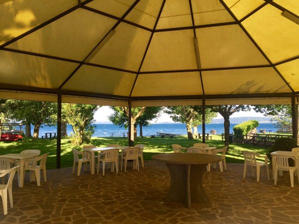 Area coperta con tavoli bianchi vista mare.