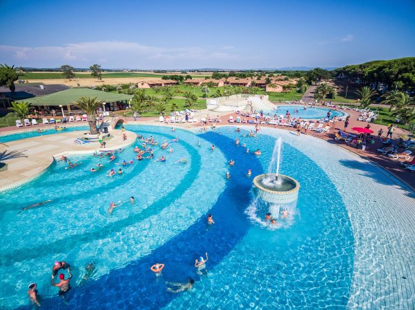 Ampia piscina con fontana centrale e molte persone che nuotano.