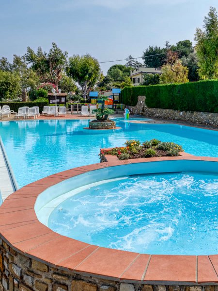 Piscina all'aperto con intorno piante e sdraio.
