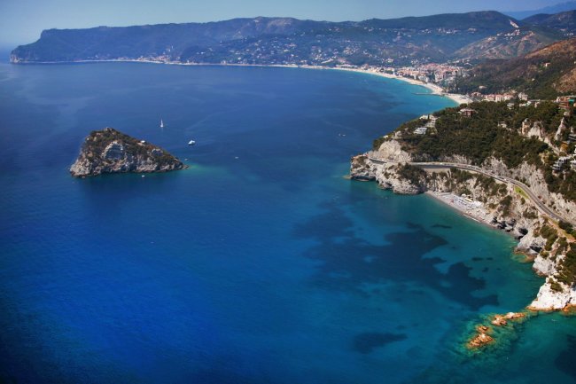 Costa con isola rocciosa e mare blu intenso.